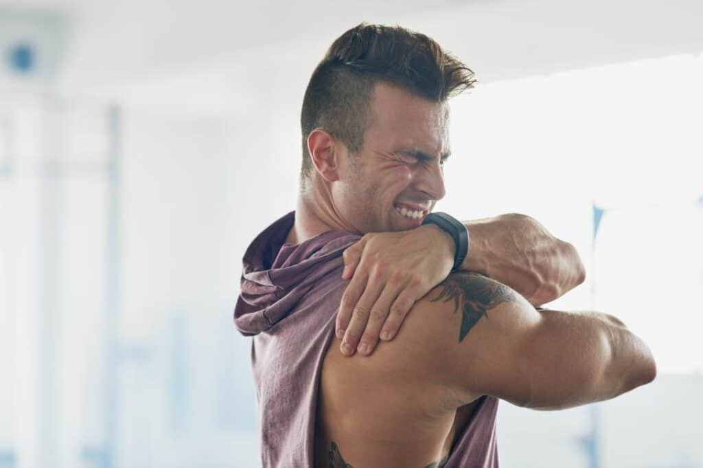 man with painful shoulder holding it and grimacing
